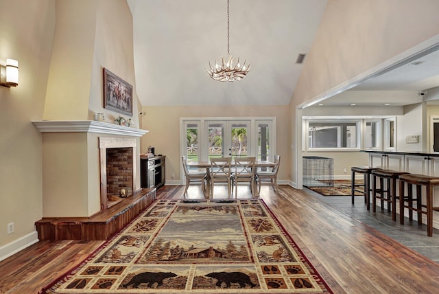 living room with high vaulted ceiling, a chandelier, a large fireplace, and hardwood / wood-style floors