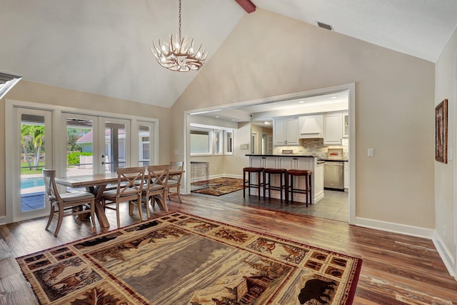 dining space featuring dark tile floors, a chandelier, high vaulted ceiling, beamed ceiling, and french doors