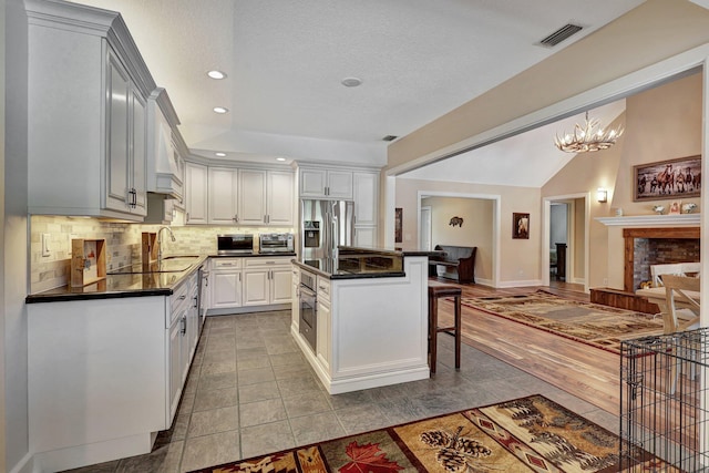 kitchen featuring white cabinetry, tile flooring, appliances with stainless steel finishes, backsplash, and a kitchen bar