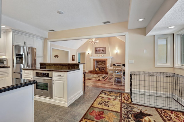 kitchen featuring white cabinetry, a kitchen island, stainless steel appliances, dark hardwood / wood-style floors, and a brick fireplace