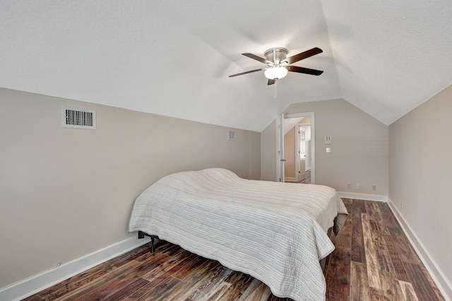 bedroom with ceiling fan, dark hardwood / wood-style flooring, a textured ceiling, and vaulted ceiling