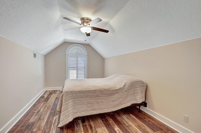 bedroom with vaulted ceiling, a textured ceiling, ceiling fan, and dark hardwood / wood-style floors