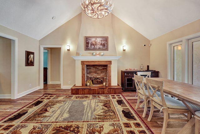 living room featuring high vaulted ceiling, an inviting chandelier, a fireplace, and wood-type flooring