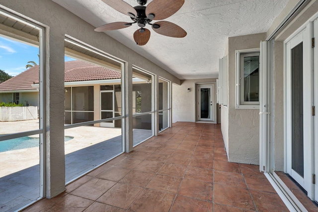 unfurnished sunroom featuring ceiling fan