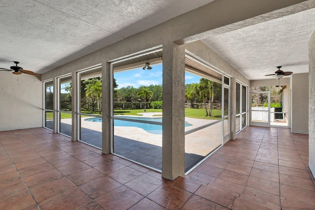 unfurnished sunroom featuring ceiling fan