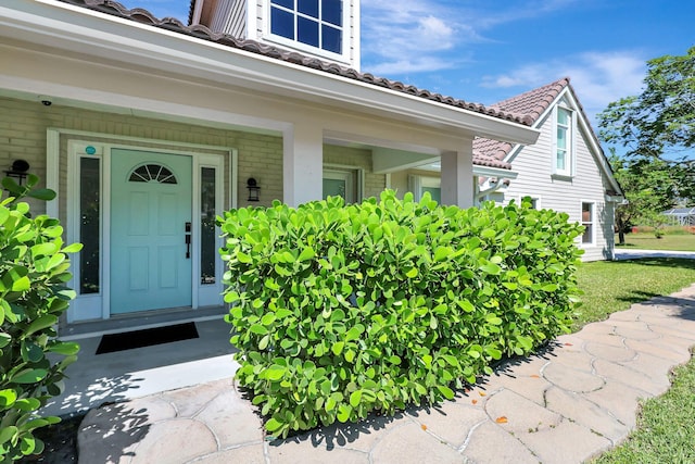 view of exterior entry featuring a yard and a porch