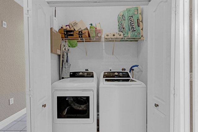 clothes washing area featuring light tile floors and washer and clothes dryer