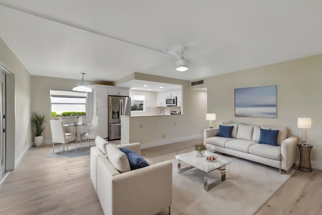 living room featuring light hardwood / wood-style flooring, ceiling fan, and sink