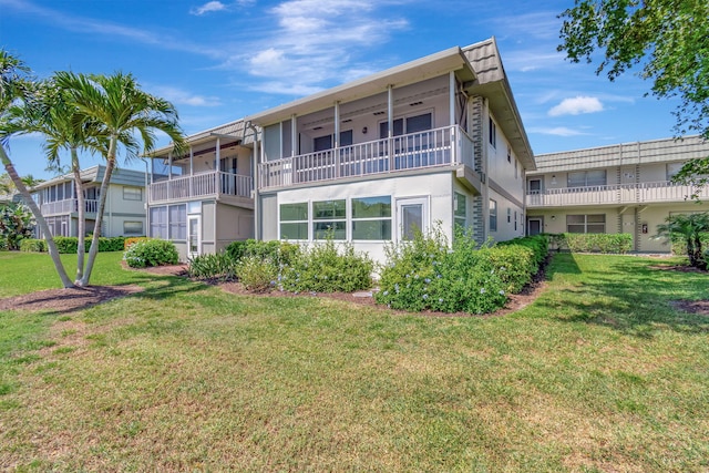 back of house with a balcony and a lawn