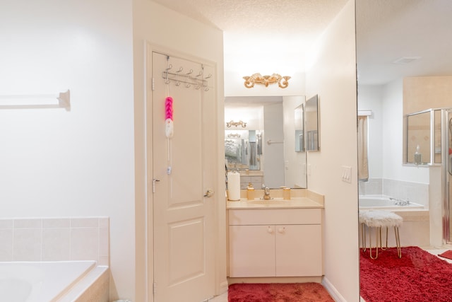 bathroom with tile flooring, a textured ceiling, large vanity, and tiled tub