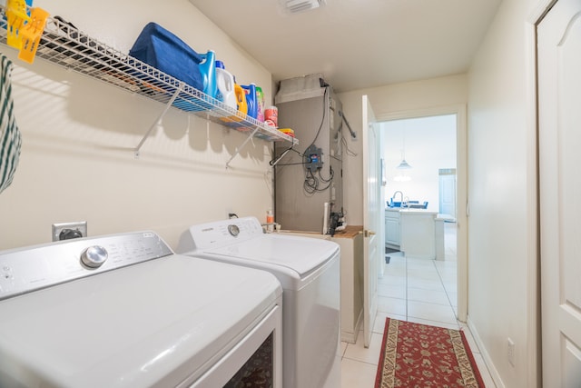 clothes washing area featuring light tile flooring and washing machine and clothes dryer