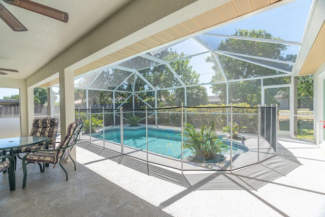 view of pool with a patio area, ceiling fan, and glass enclosure