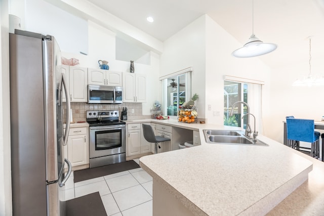 kitchen featuring pendant lighting, high vaulted ceiling, appliances with stainless steel finishes, light tile floors, and sink