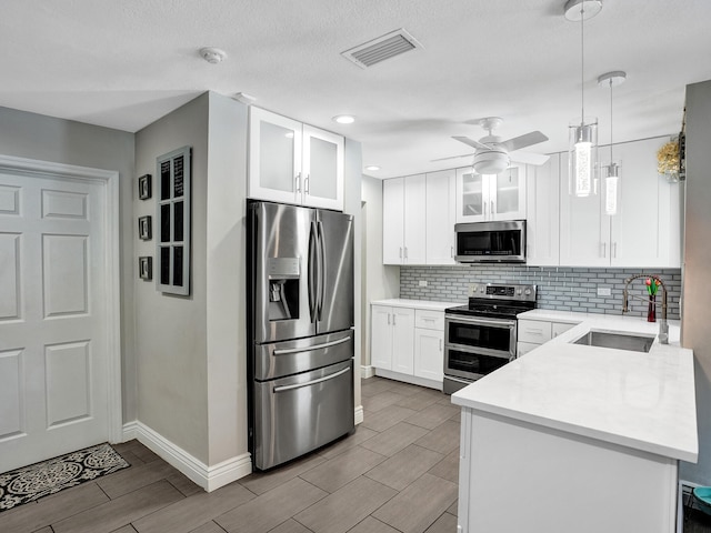 kitchen with stainless steel appliances, ceiling fan, sink, pendant lighting, and white cabinetry