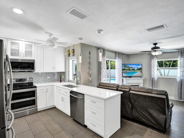 kitchen featuring stainless steel appliances, ceiling fan, sink, decorative light fixtures, and white cabinetry