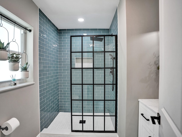 bathroom with a tile shower and vanity