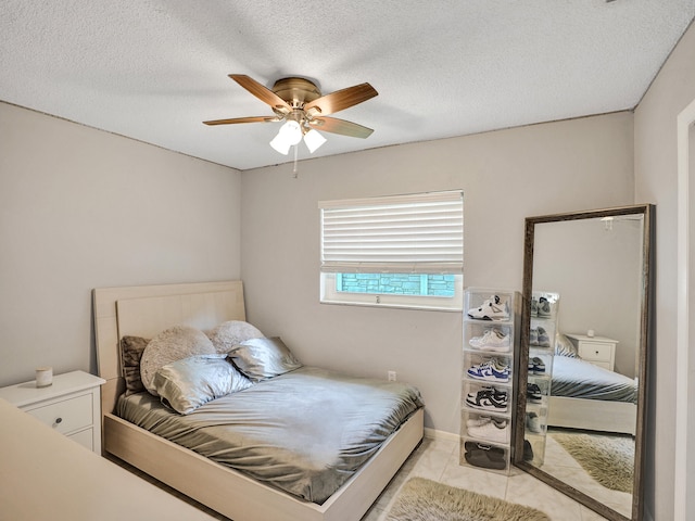 tiled bedroom featuring ceiling fan and a textured ceiling