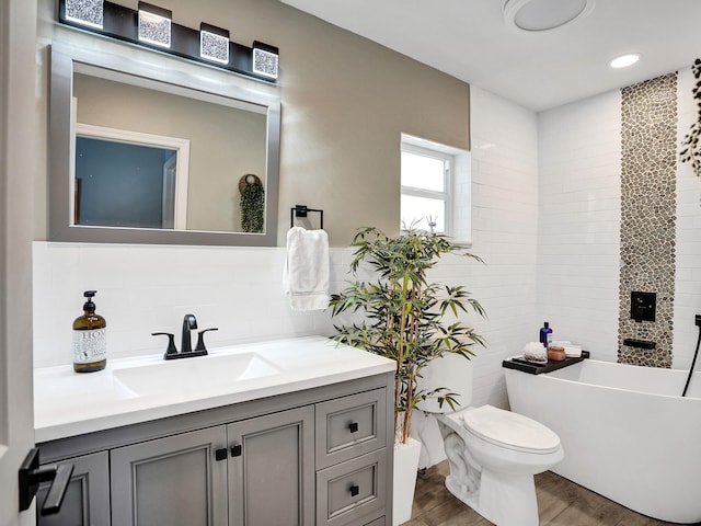 bathroom with hardwood / wood-style floors, toilet, decorative backsplash, a bathtub, and vanity