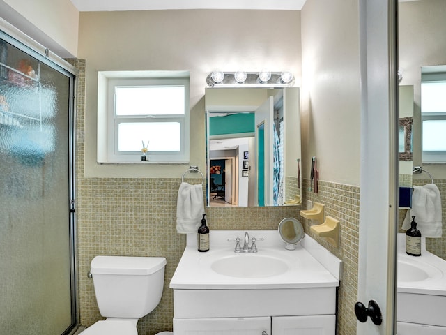 bathroom with vanity, a shower with shower door, tile walls, and toilet