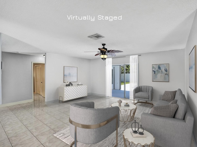 living room featuring ceiling fan, light tile patterned floors, and a textured ceiling