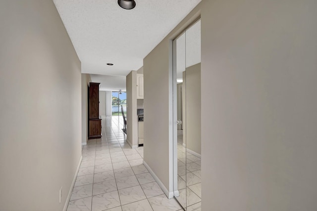 corridor featuring a textured ceiling and light tile floors