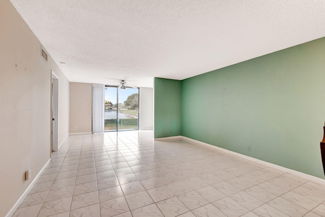 unfurnished room featuring a textured ceiling, ceiling fan, and light tile floors