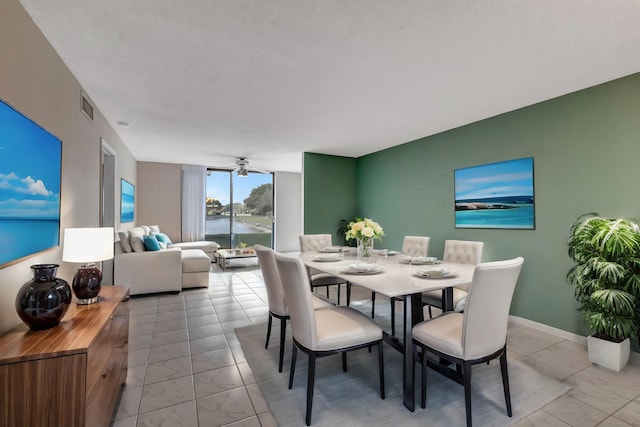 tiled dining area with ceiling fan and a water view