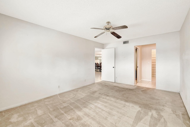 carpeted spare room featuring a textured ceiling and ceiling fan