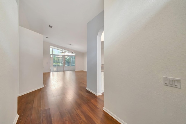 hallway with dark wood-type flooring and vaulted ceiling