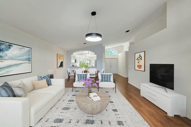 living room with hardwood / wood-style floors, an inviting chandelier, and lofted ceiling