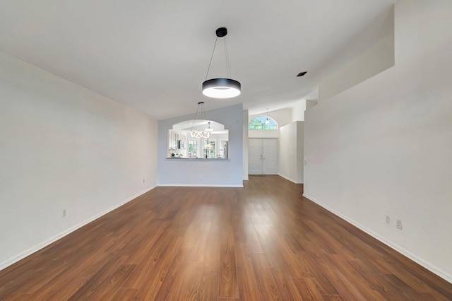 unfurnished dining area with dark hardwood / wood-style flooring, an inviting chandelier, and vaulted ceiling