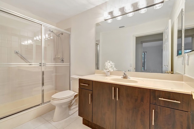 bathroom featuring toilet, vanity, tile patterned floors, and a shower with door