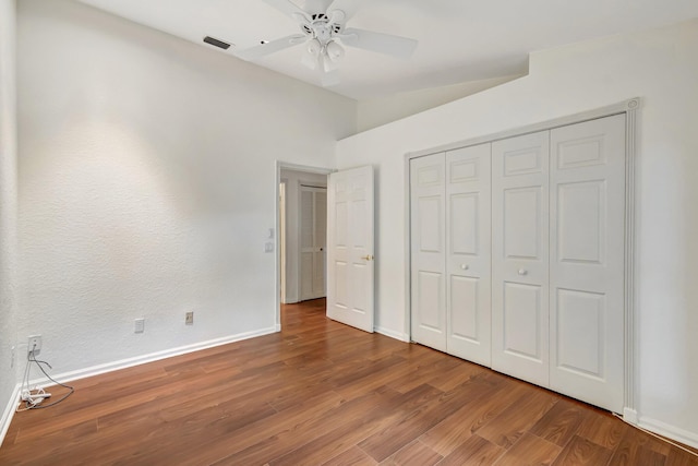 unfurnished bedroom featuring wood-type flooring, a closet, vaulted ceiling, and ceiling fan