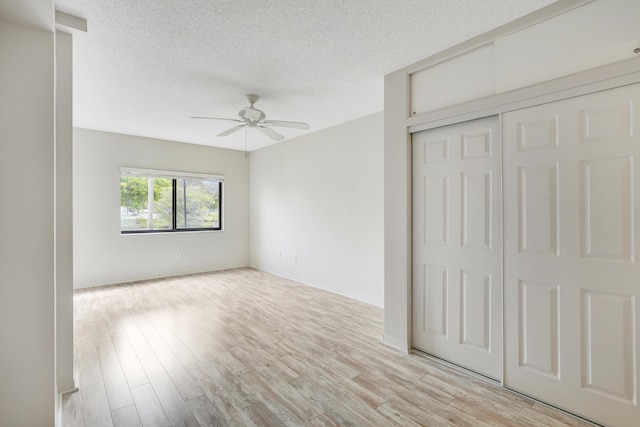 unfurnished bedroom featuring a closet, ceiling fan, light hardwood / wood-style flooring, and a textured ceiling