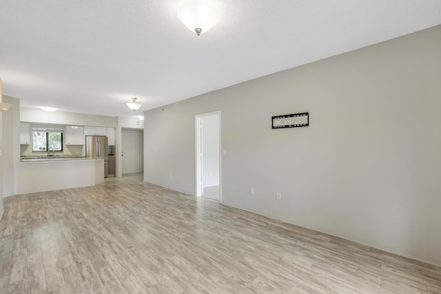 unfurnished living room with light hardwood / wood-style floors and sink