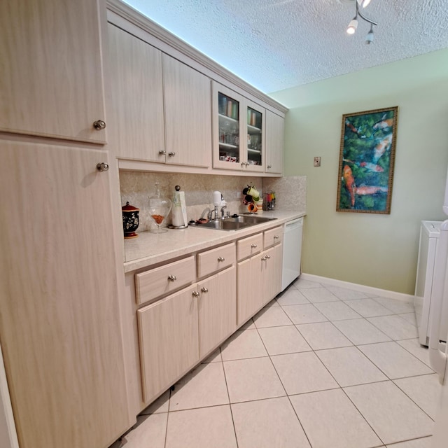 kitchen featuring tasteful backsplash, sink, light tile patterned floors, white dishwasher, and a textured ceiling