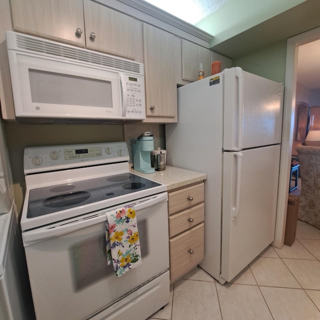 kitchen with light tile patterned floors, light brown cabinetry, and white appliances