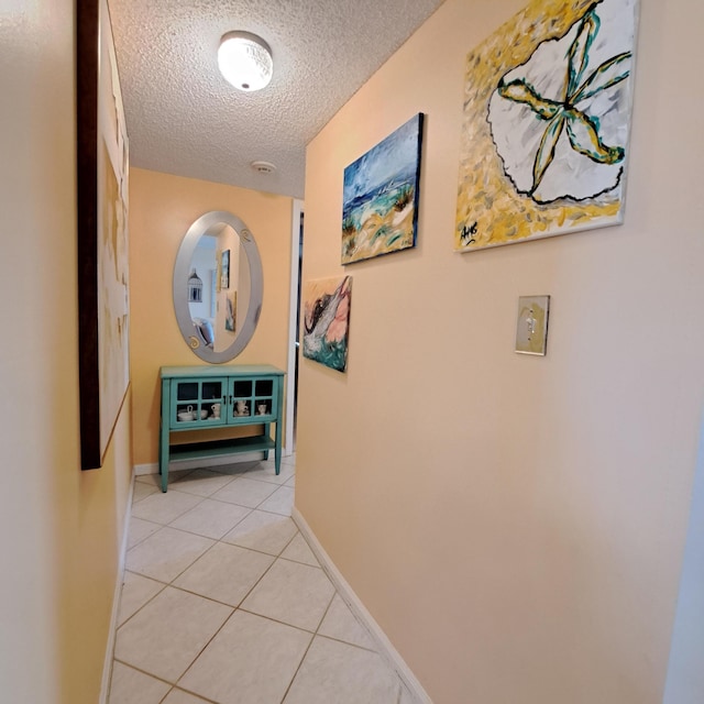 corridor with light tile patterned flooring and a textured ceiling