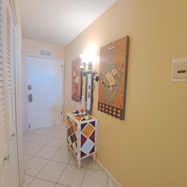 corridor with light tile patterned flooring and a textured ceiling