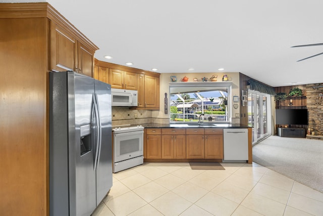 kitchen with backsplash, white appliances, sink, and light tile floors