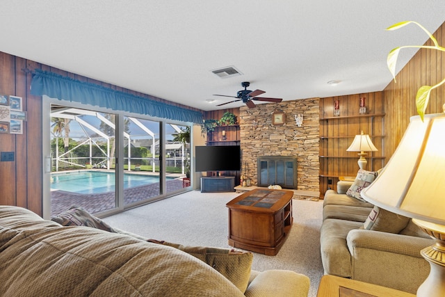 living room with wooden walls, plenty of natural light, ceiling fan, and a fireplace