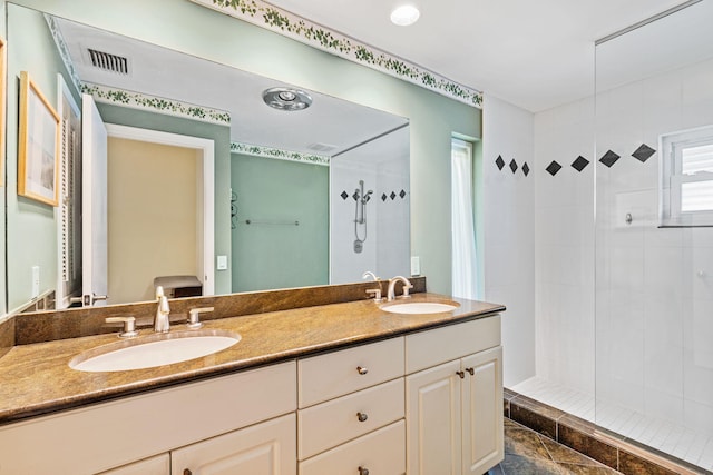 bathroom with tiled shower, tile floors, double sink, and large vanity