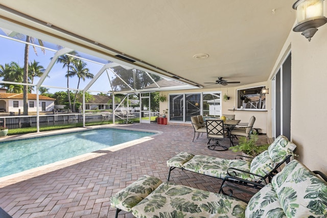 view of swimming pool with ceiling fan, a lanai, and a patio