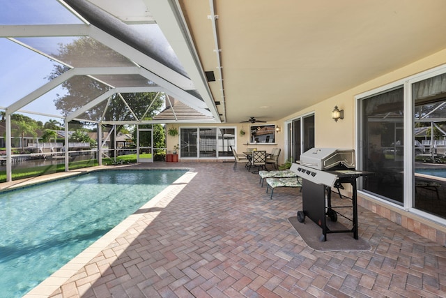 view of pool featuring glass enclosure, a grill, ceiling fan, and a patio area