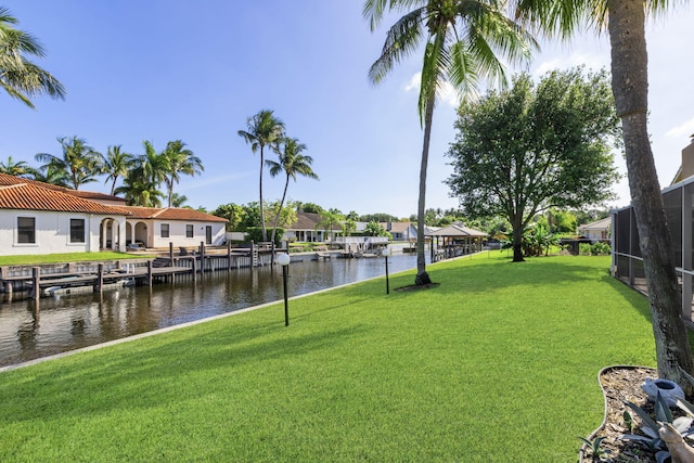 view of dock with a water view, a yard, and a lanai