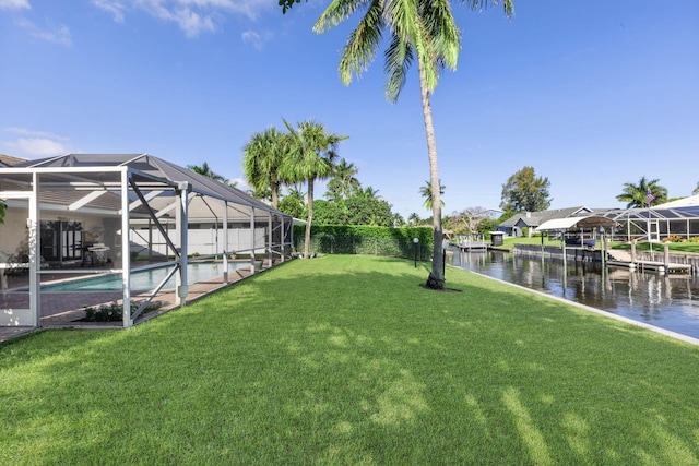 view of yard with glass enclosure, a boat dock, and a water view