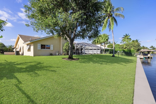 view of yard featuring a lanai, central air condition unit, and a dock