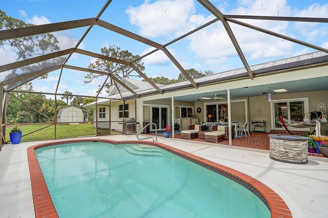 view of pool with glass enclosure, a patio area, a shed, an outdoor living space, and grilling area