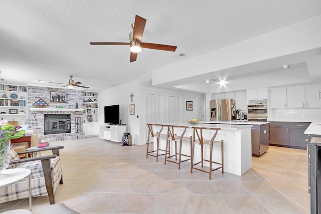 kitchen featuring built in features, stainless steel refrigerator with ice dispenser, a center island, and light tile patterned floors