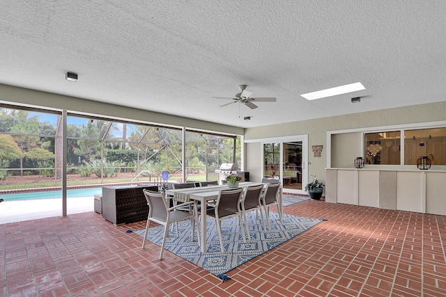 sunroom featuring ceiling fan and a skylight